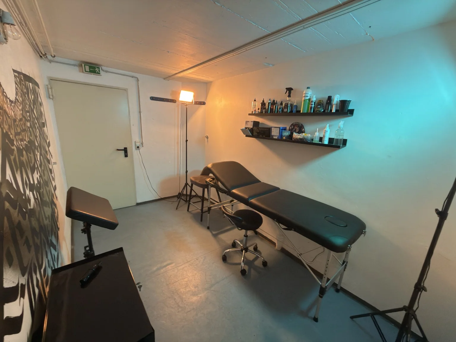 Tattoo-Liege im Studio mit Orange-Türkis-Beleuchtung
